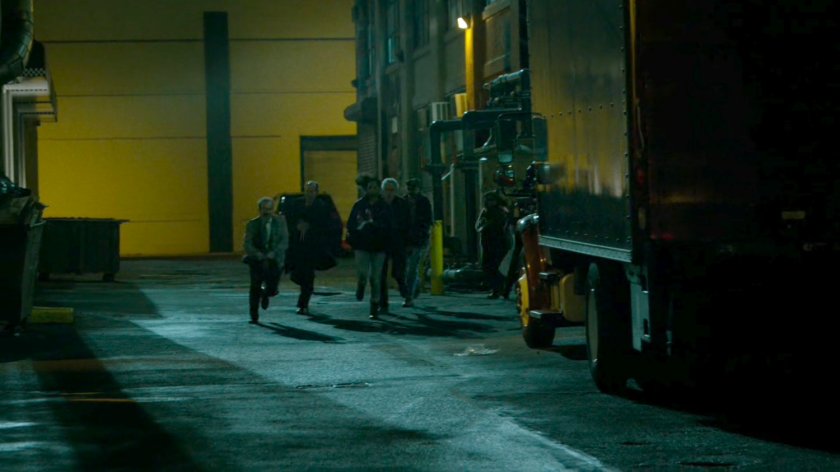 Hostages running in an alley outside abandoned warehouse.