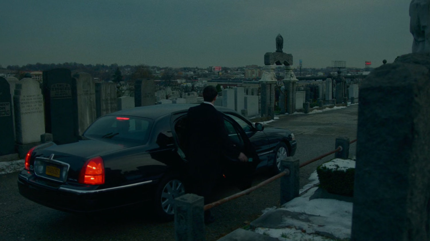 Matt gets into a car at a snowy cemetery.