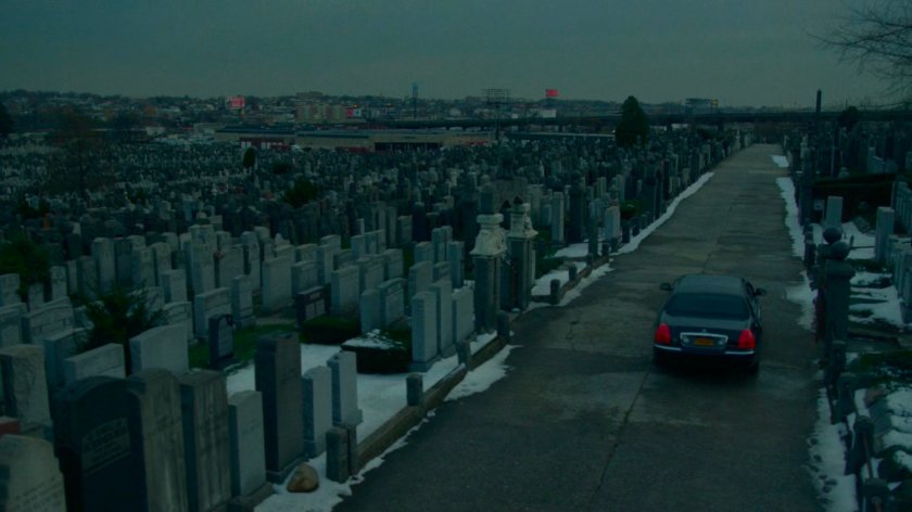 A car drives off from a snowy cemetery.