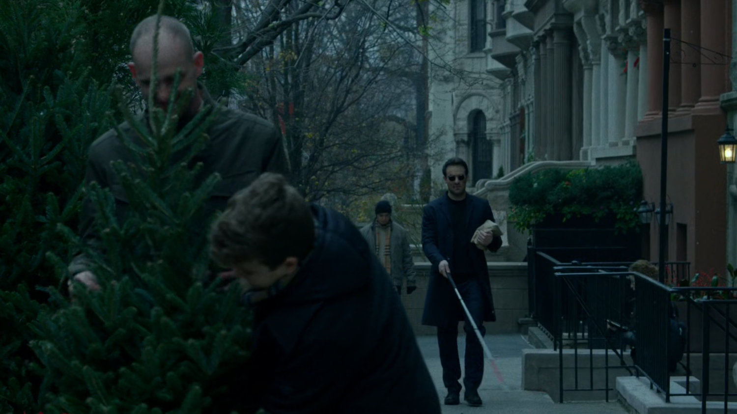Matt walking along a sidewalk past people buying Christmas Tree.