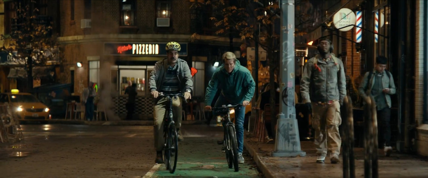 Peter and Wade riding bikes along city street at night.