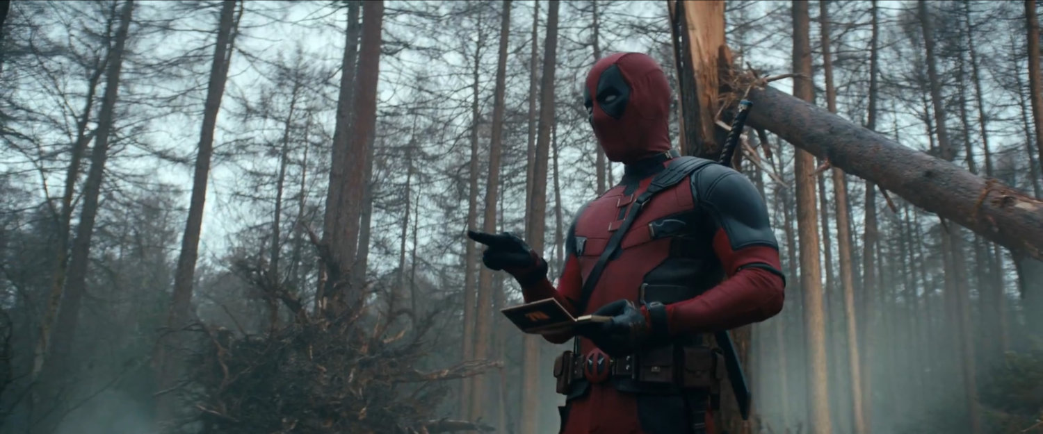 Deadpool standing in woods.