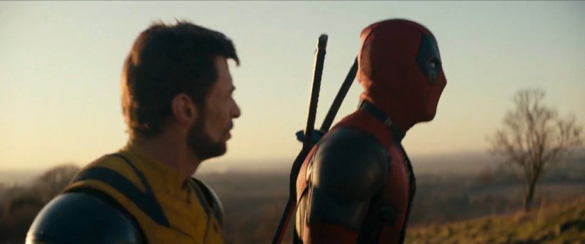 Wolverine and Deadpool walking across hilly countryside.