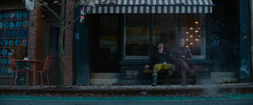 Wolverine and Deadpool sitting outside shop.