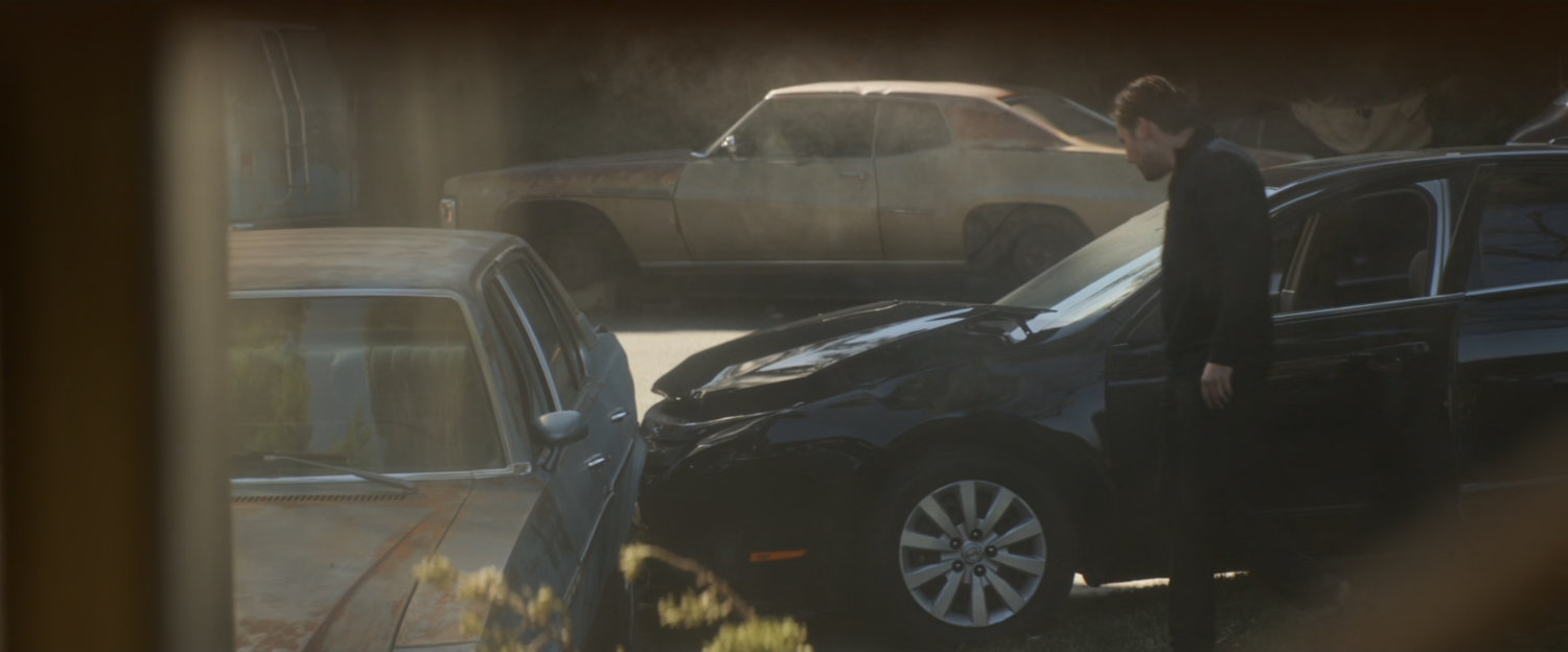 Zemo inspects a crashed car outside Vasily Karpov's house.