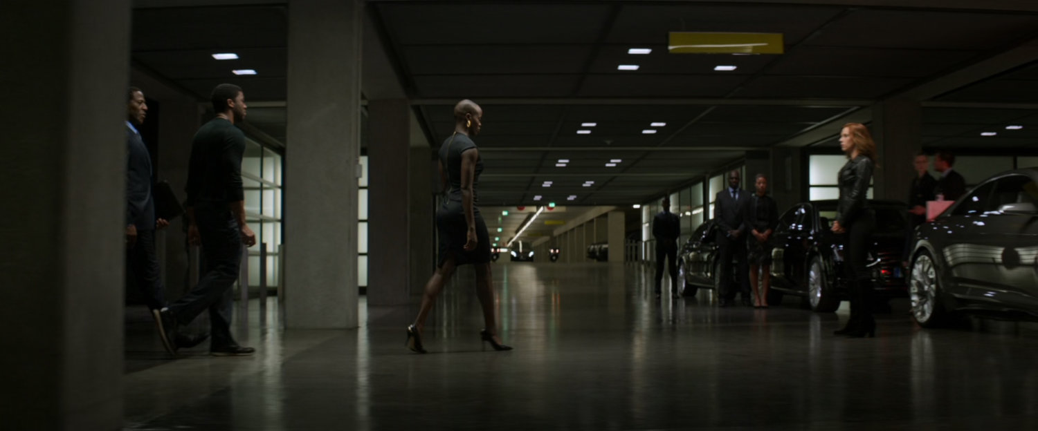 T'challa and his entourage walking into an underground parking lot.