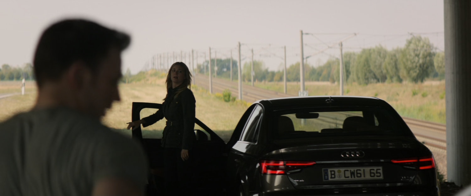 Sharon exits car under a Berlin underpass by railway.