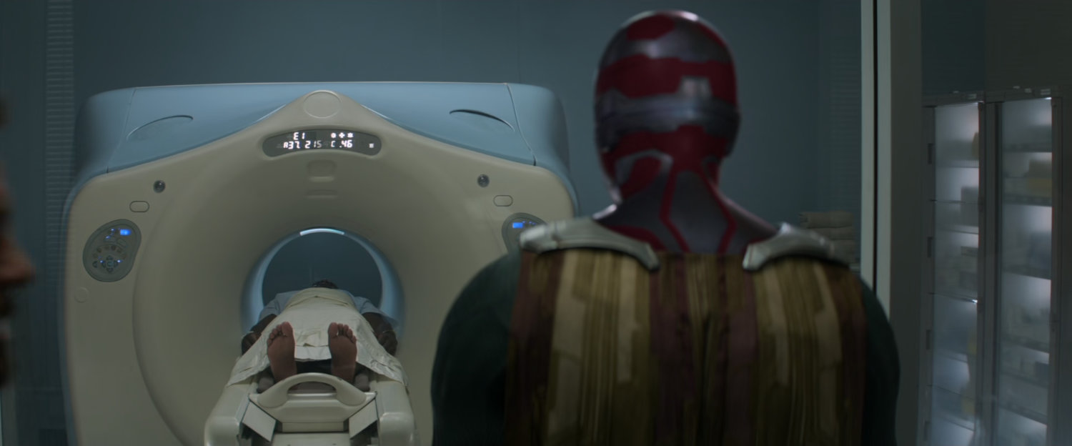 The Vision watches Rhodes enter an MRI scanner at a hospital.