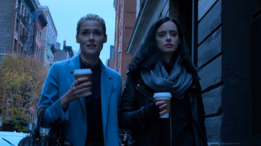 Trish and Jessica walking along sidewalk with coffee cups.