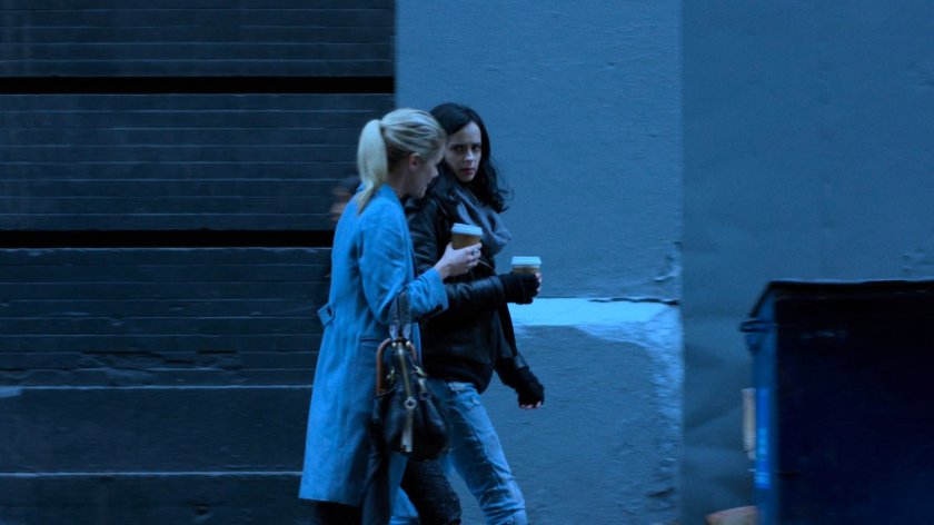 Trish and Jessica walking along sidewalk with coffee cups.