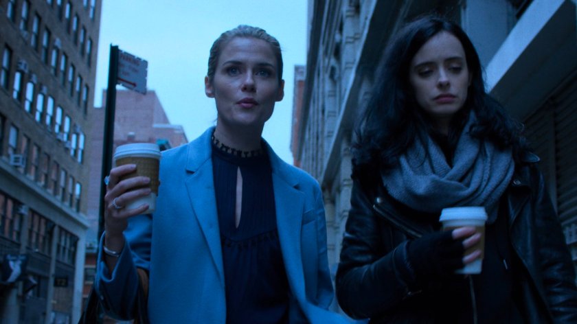 Trish and Jessica walking along sidewalk with coffee cups.