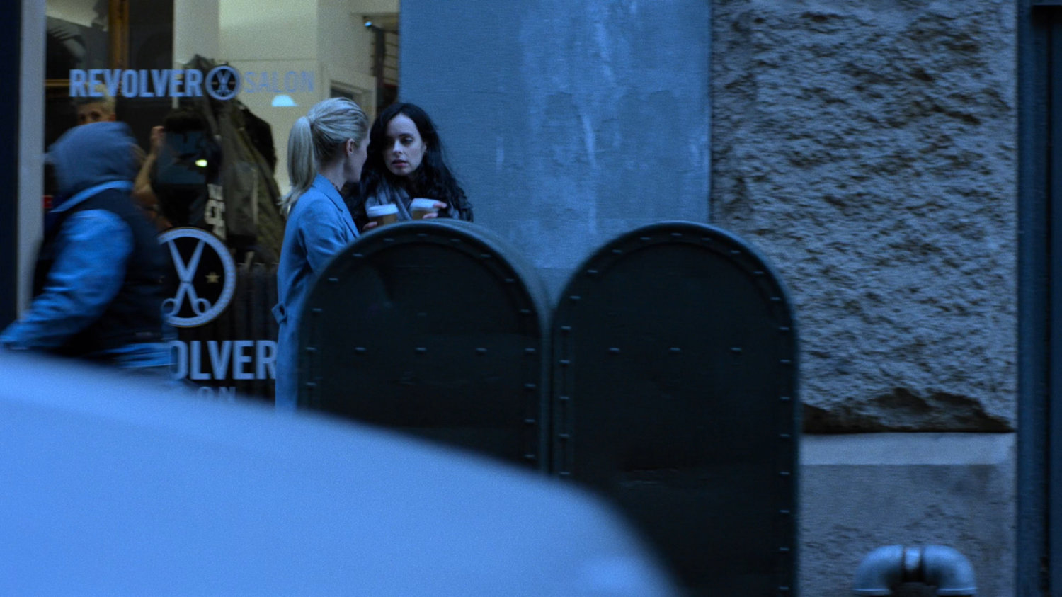 Trish and Jessica walking along sidewalk with coffee cups.