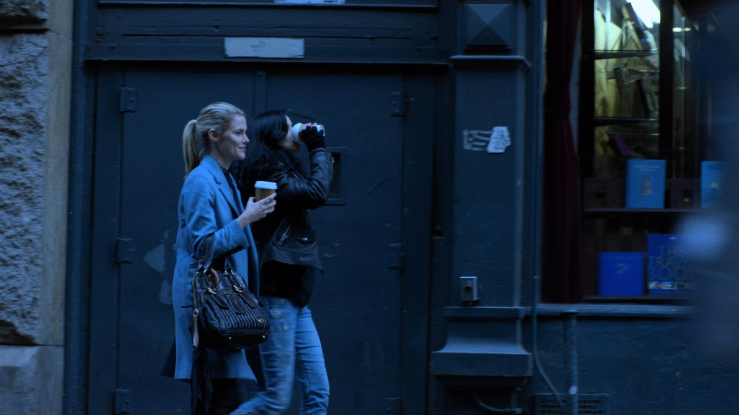 Trish and Jessica walking along sidewalk with coffee cups.