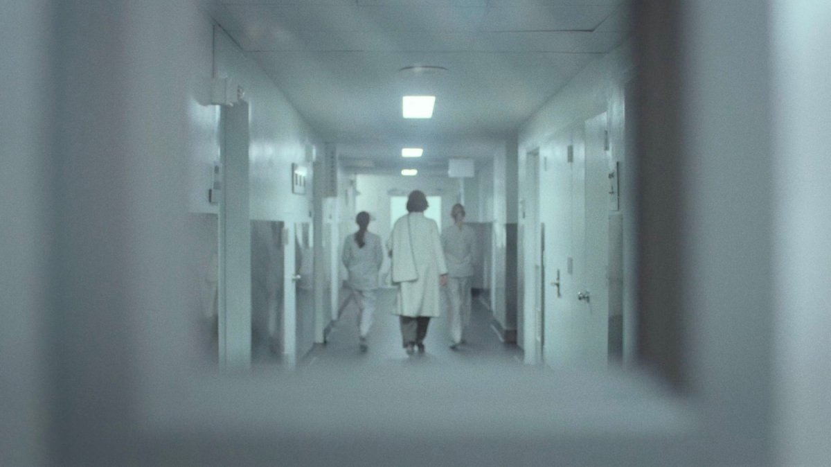 Alexandra Reid walking through white corridor of hospital.