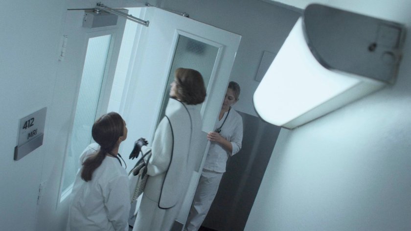 Alexandra Reid entering MRI room with two nurses in white corridor of hospital.