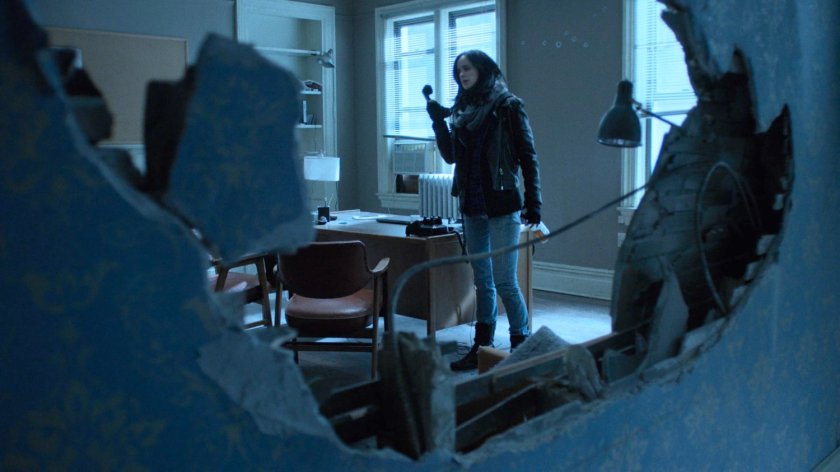 Shot looking through a hole in the wall of Alias Investigations.