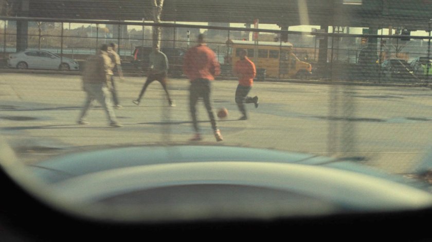 View from city bus of men playing basketball.