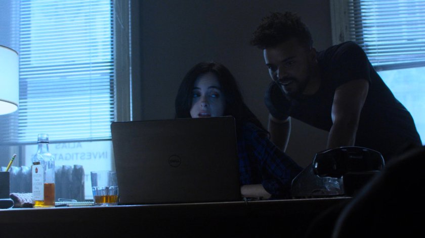 Jessica Jones and Malcolm looks at her computer in Alias Investigations office.