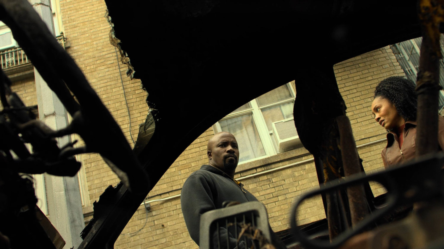 Luke and Misty as seen from inside burned out car on Harlem street.