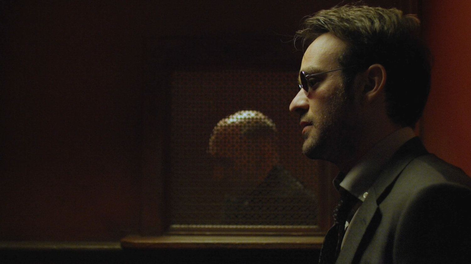 Matt talking to Father Lantom in confessional.