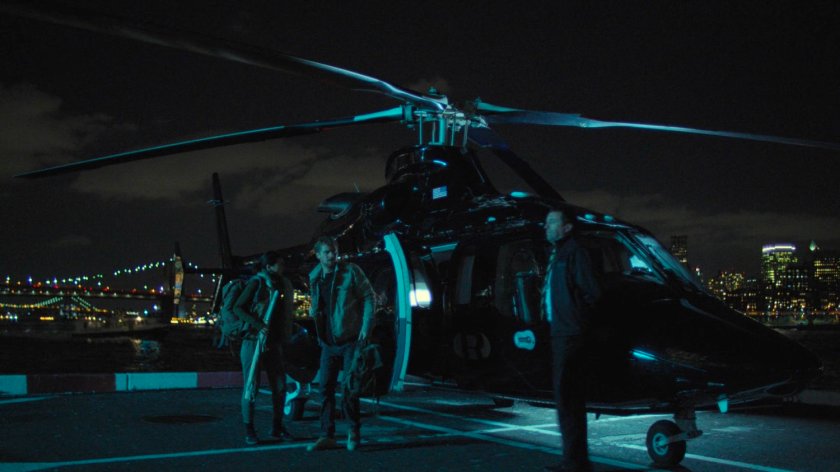 Colleen and Danny exit a helicopter at a city heliport.
