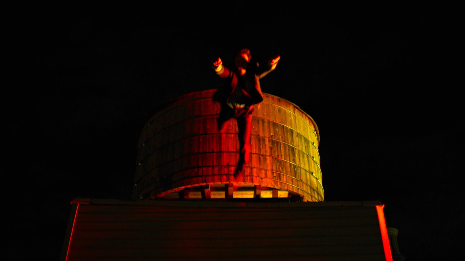 Matt leaping from his rooftop in front of a water tower.
