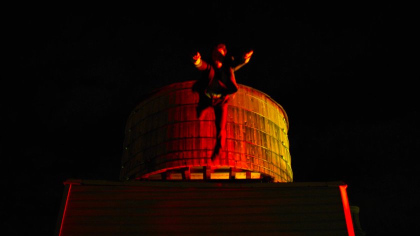 Matt leaping from his rooftop in front of a water tower.