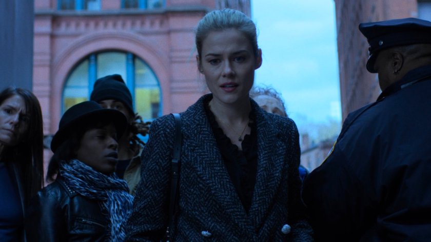 Trish and a crowd look at a car blocking the street.