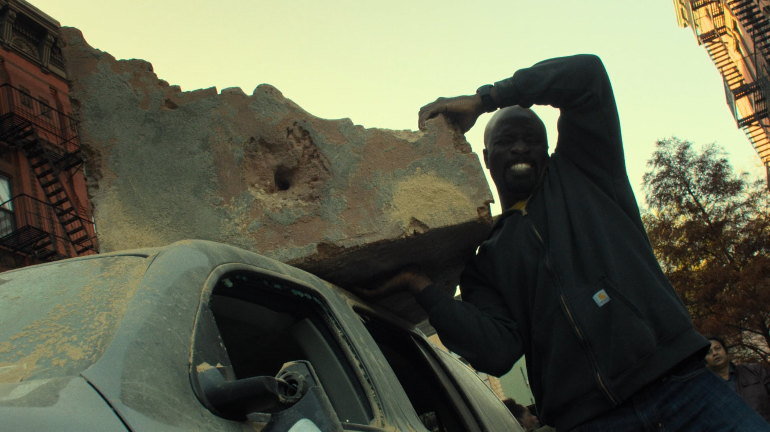 Luke lifts a giant piece of rubble off a car roof.