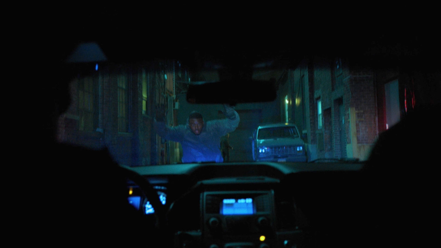 Cole Miller raises his hands towards the police in the alley behind the Tsukamoto workshop.