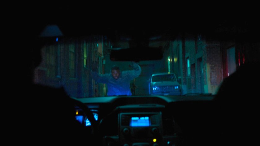 Cole Miller raises his hands towards the police in the alley behind the Tsukamoto workshop.