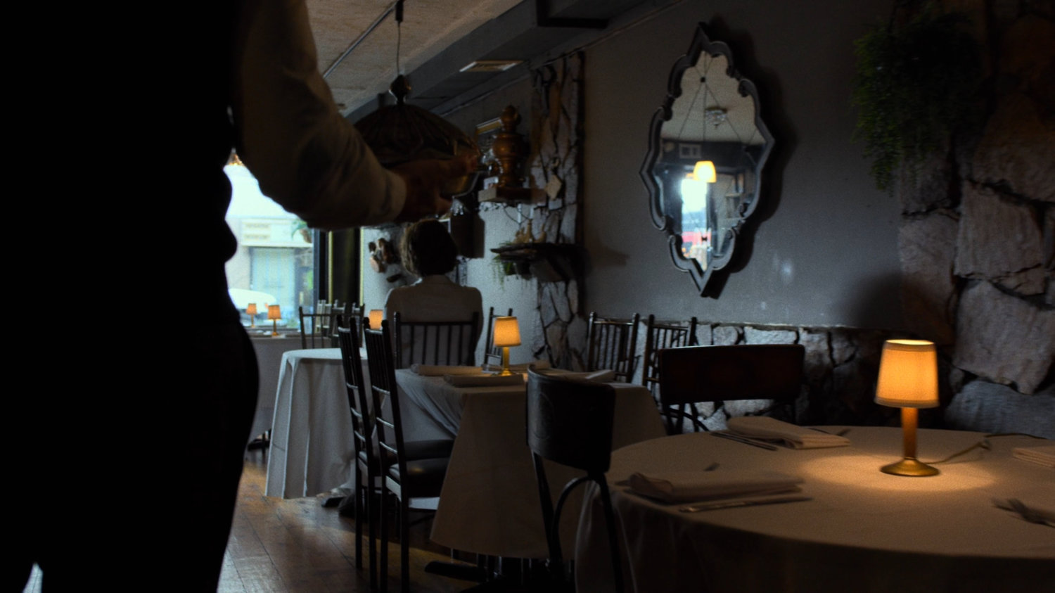 Server walking through empty Turkish restaurant towards Alexandra.
