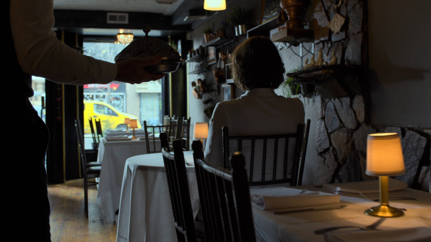 Server walking through empty Turkish restaurant towards Alexandra.