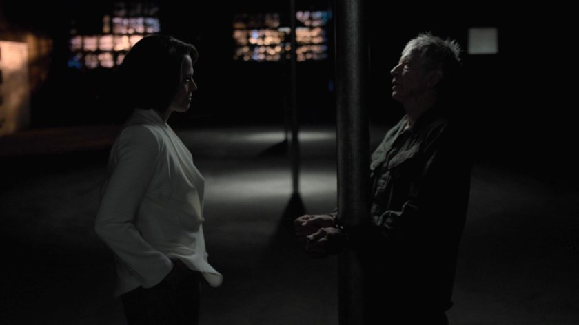 Alexandra confronts Stick in a dark warehouse.