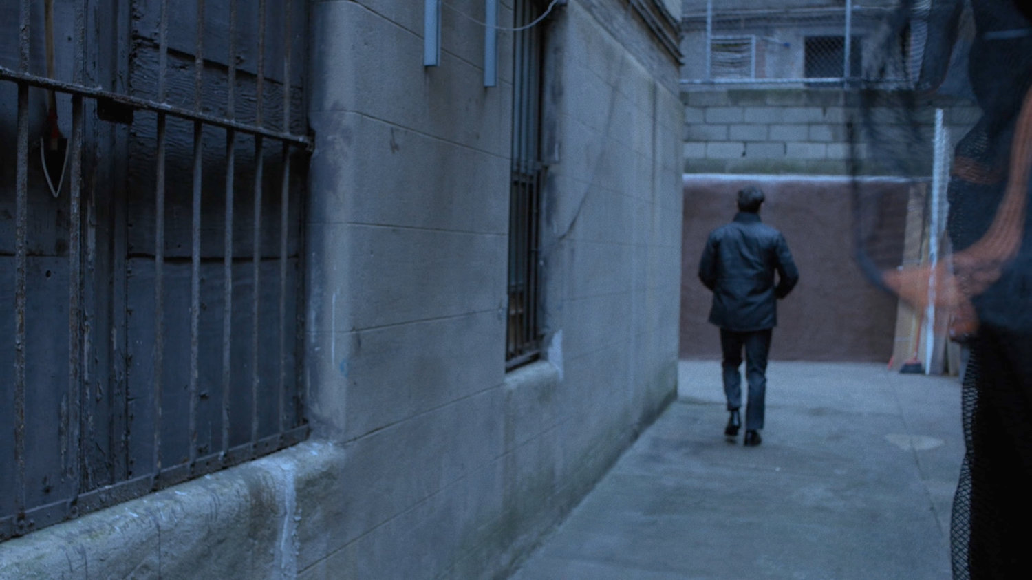 Matt walking around corner in alley.