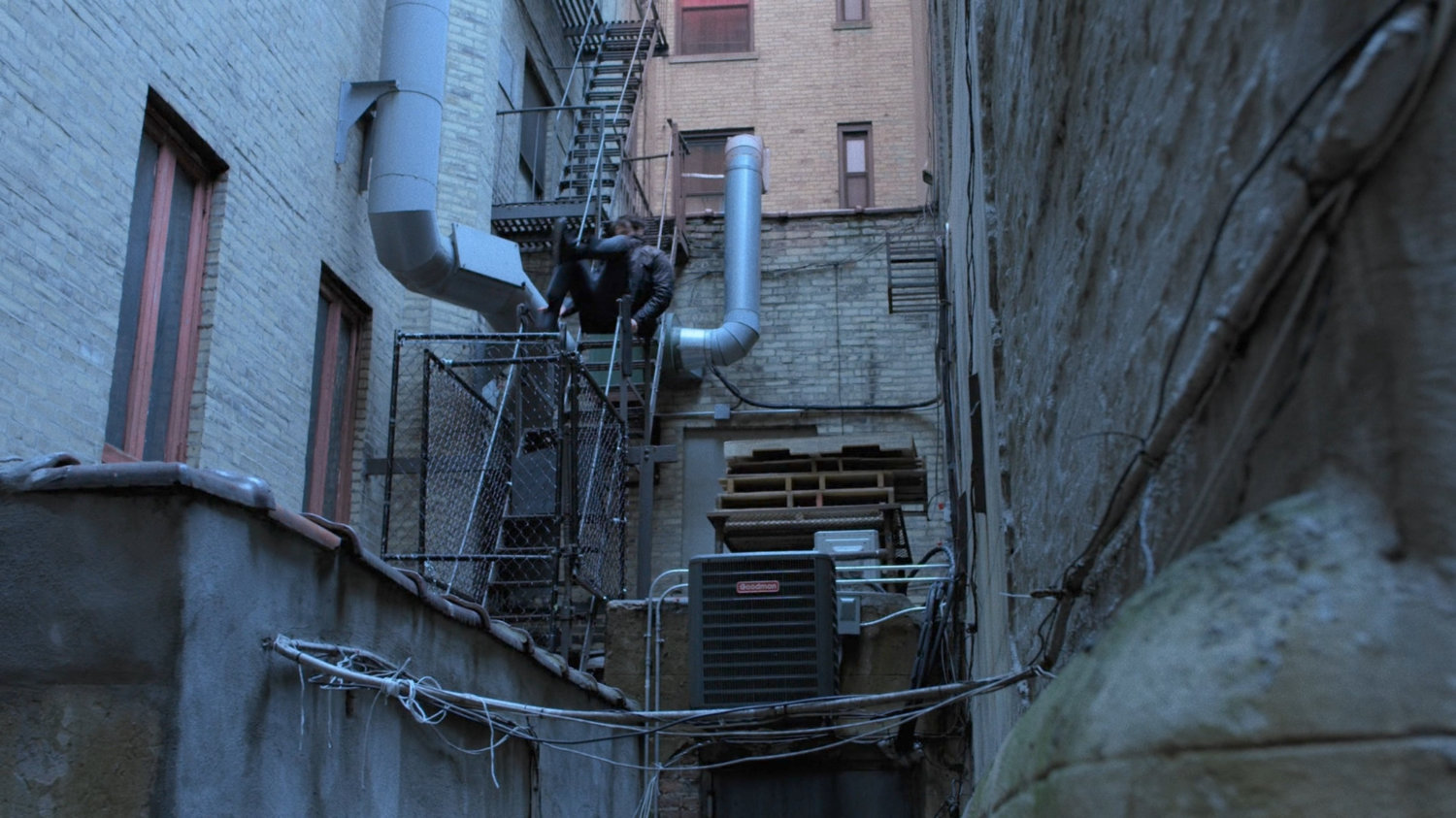 Matt leaping onto fire escape in back of alley.