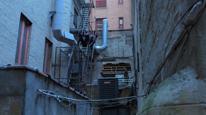 Matt leaping onto fire escape in back of alley.