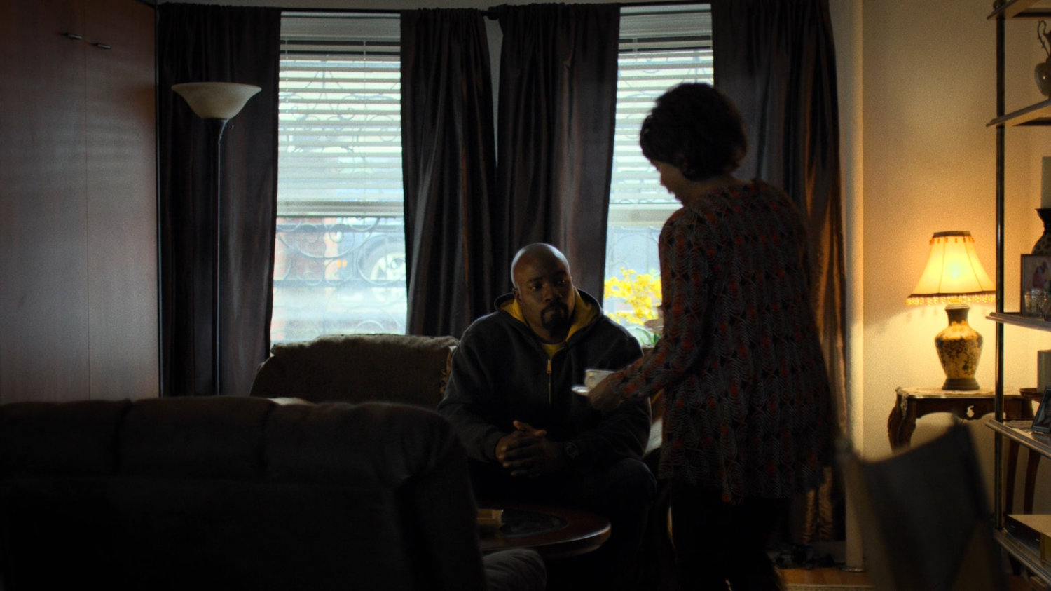 Luke sits with Dolores Miller in her apartment.