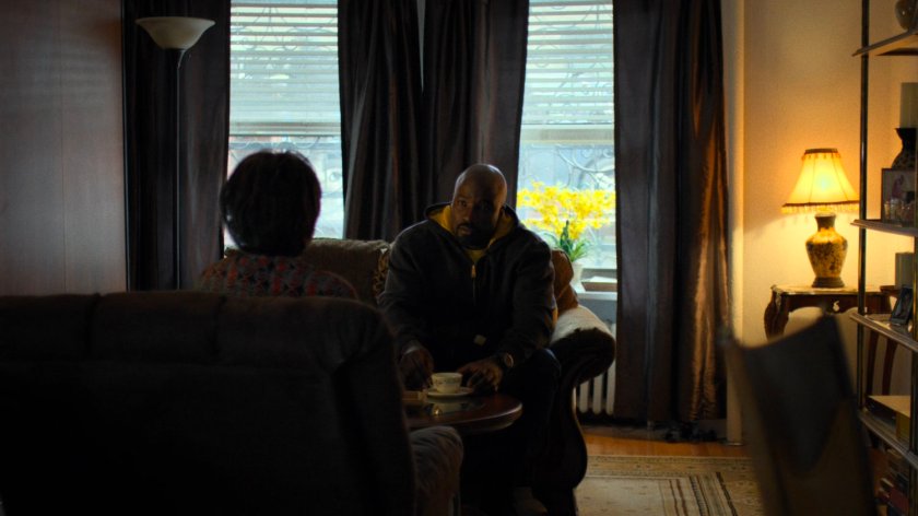 Luke sits with Dolores Miller in her apartment.
