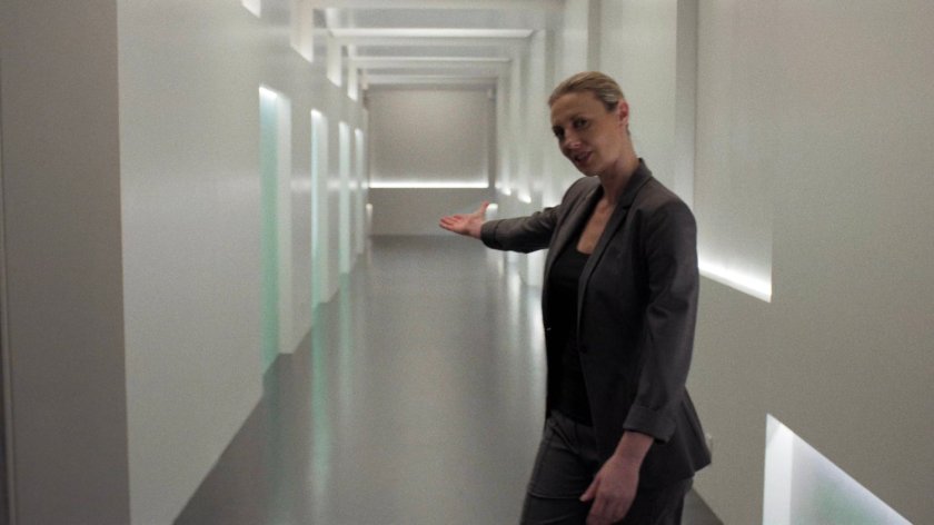 Woman gestures down empty hallway of Midland Circle Financial skyscraper.