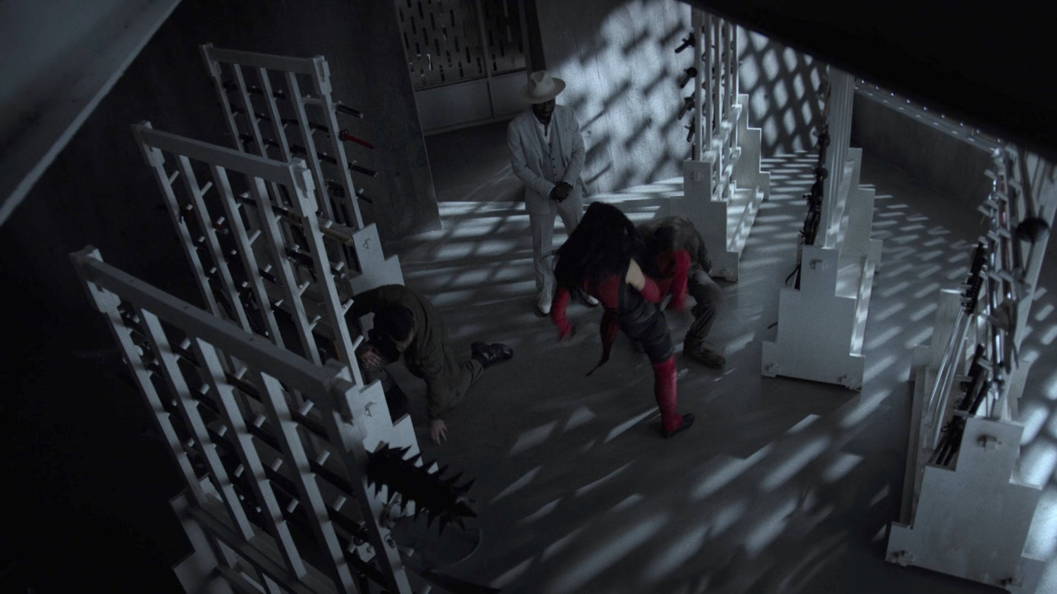 Elektra fights two thugs in the Hand compound, while Sowande looks on.