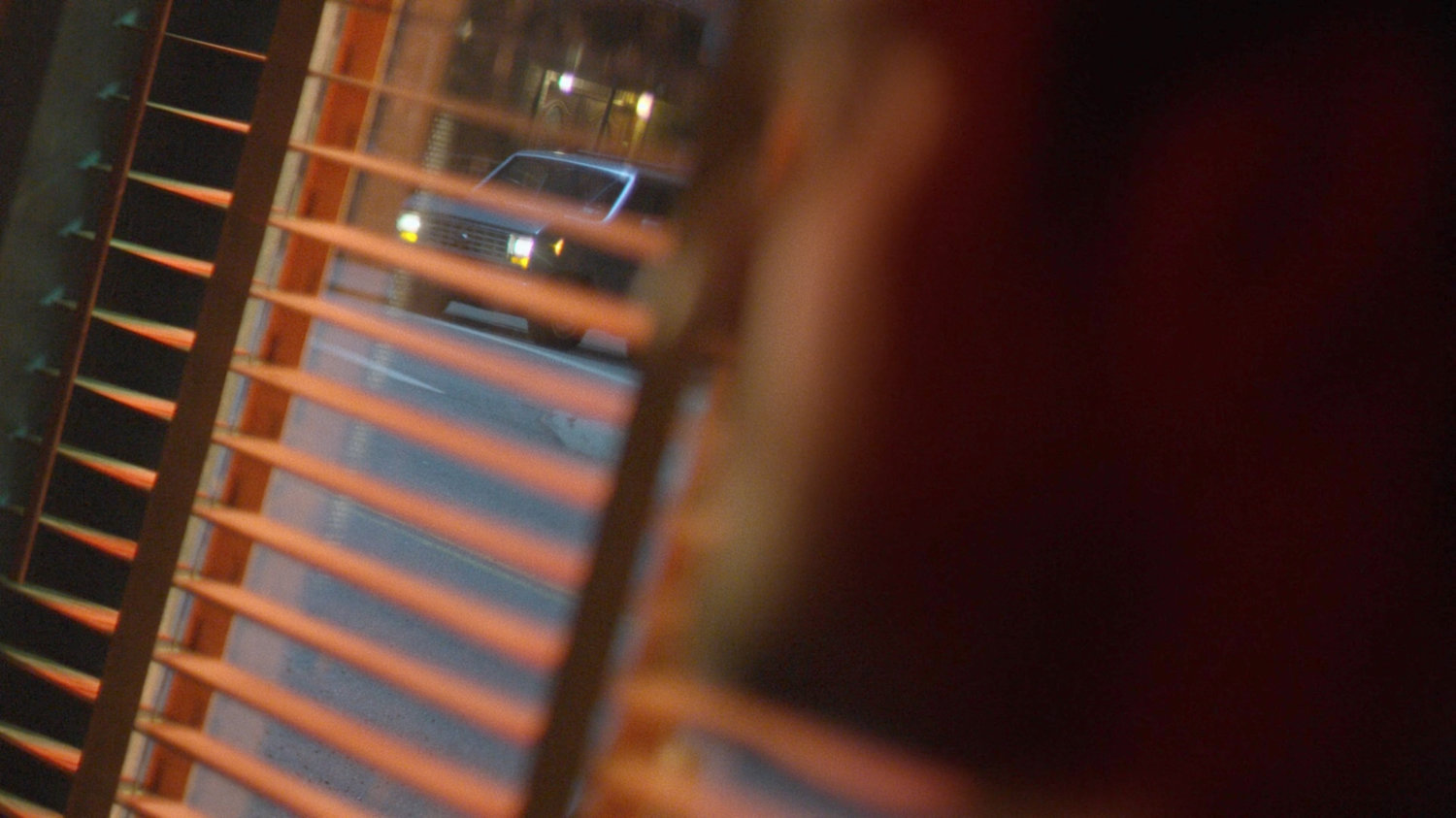 A van parked across the street from the Royal Dragon Chinese Restaurant as seen through mini blinds.