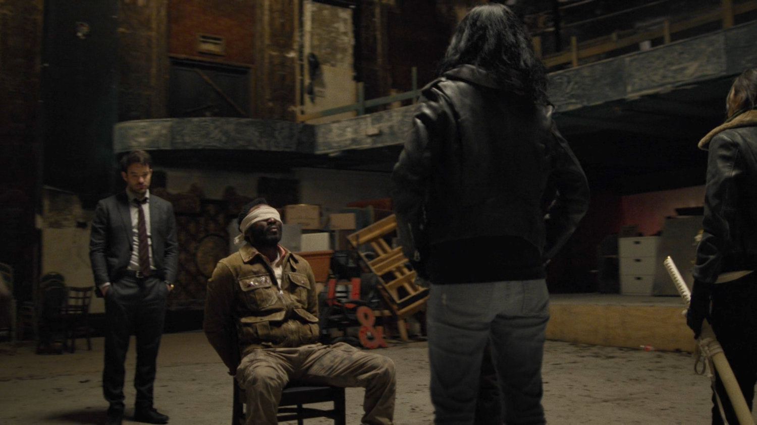 Matt and Jessica talk with captive Sowande in a derelict theater.
