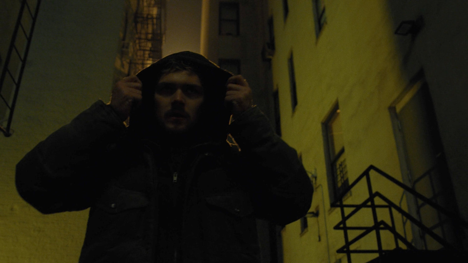 Danny walks through a backlit alley.