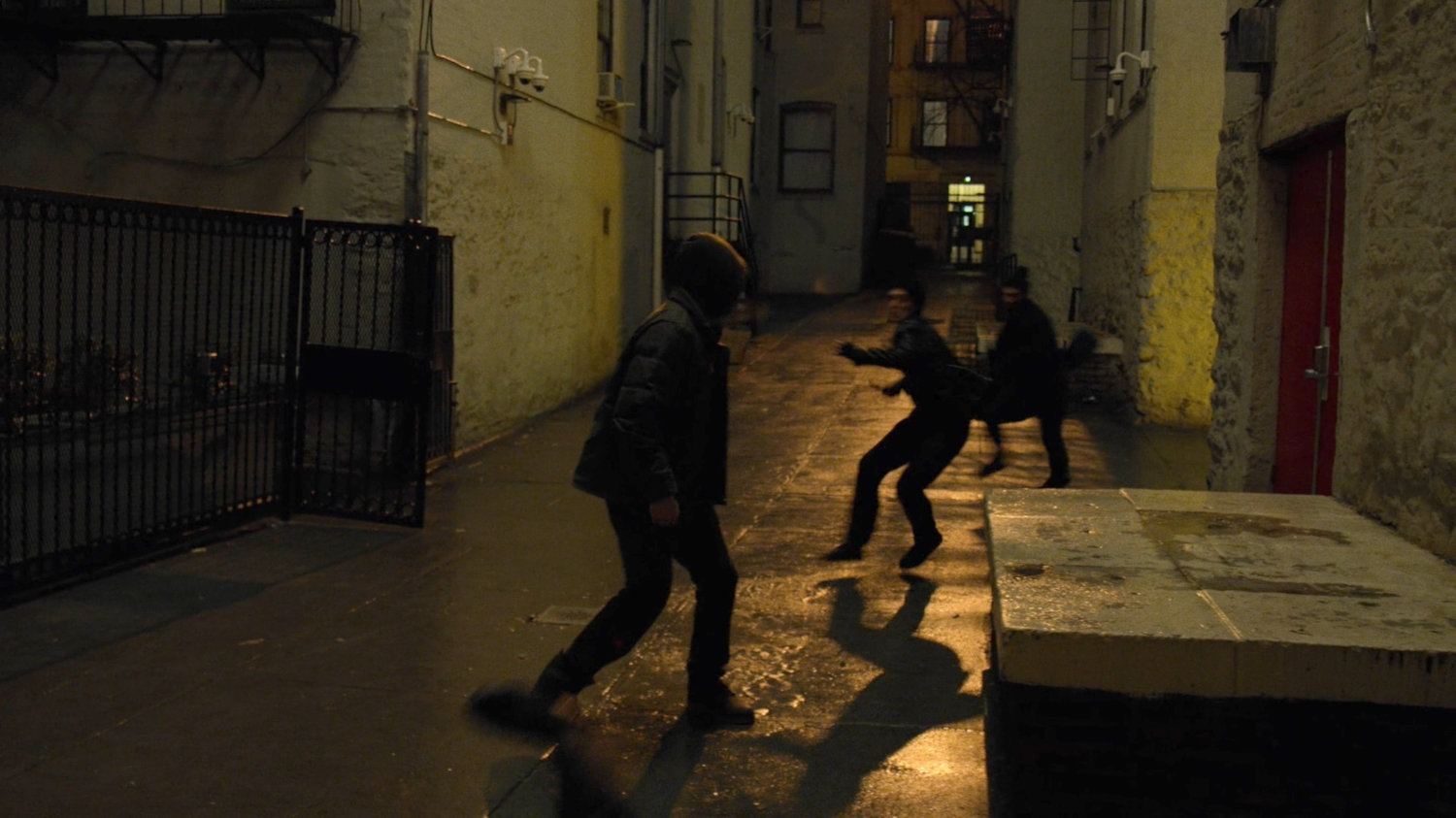 Danny fights two goons in a backlit alley.