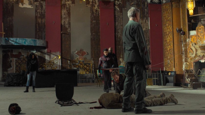 Stick stands over an headless Sowande as the Defenders look on in a derelict theater.