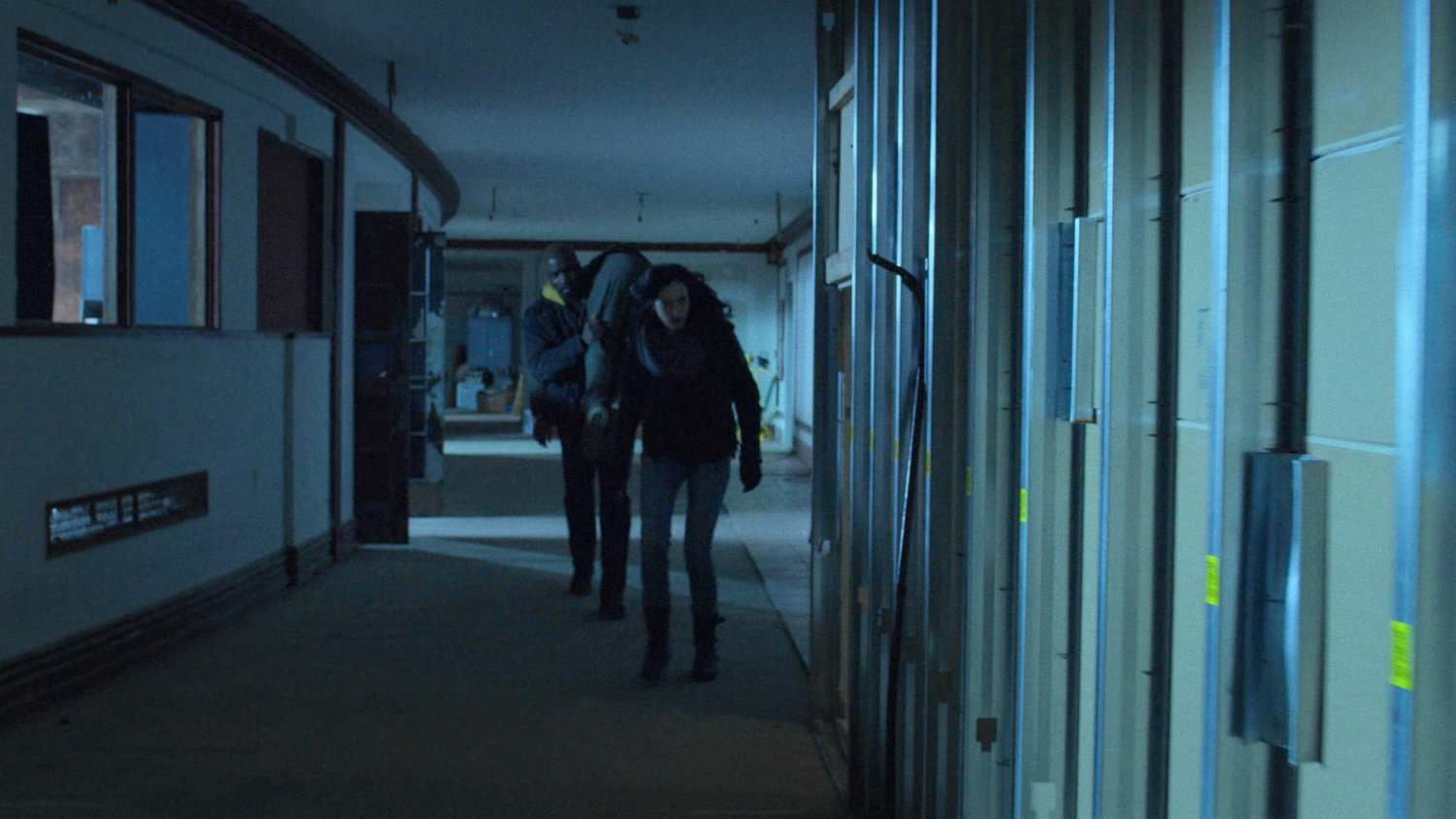 Luke carriers Danny as he and Jessica look for someplace to stash him in a dilapidated theater.