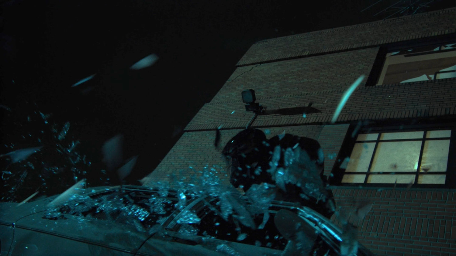 Elektra crashes into a parked car after jumping out a window of a dilapidated theater.