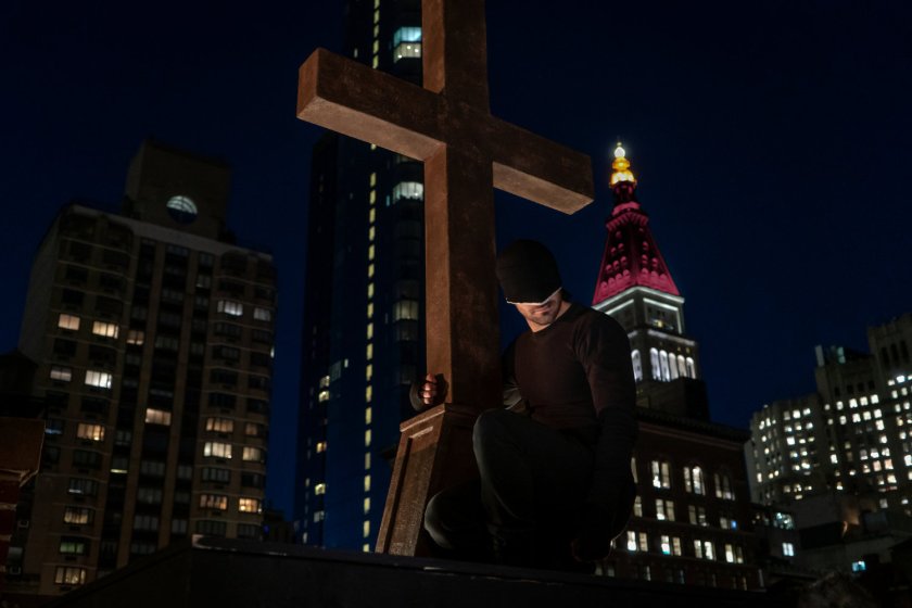 Promotional image of the Man in Black on a church rooftop at night, clinging to the cross.