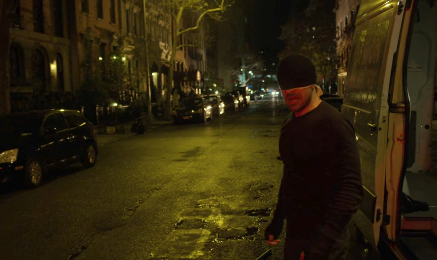 The Man in Black standing on a dark street outside van.